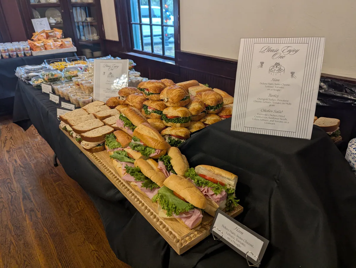 Catered spread of sandwiches, croissants, salads, and sides